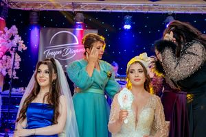 Wedding celebration with attendees in formal attire dancing under colorful venue lighting.