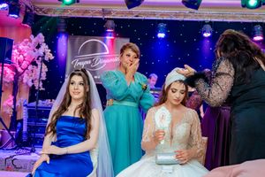 Wedding celebration with bridesmaids in turquoise dresses and bride in white gown under vibrant lighting.