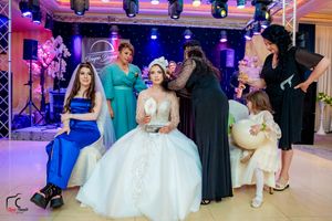 Wedding reception venue decorated with dramatic lighting and guests in formal attire dancing.