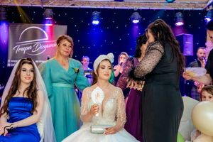 Wedding reception party scene with colorful lighting and guests in formal attire dancing and mingling on the dance floor.