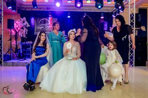 Wedding reception venue with colorful purple and blue lighting showing guests dancing and celebrating on the dance floor.