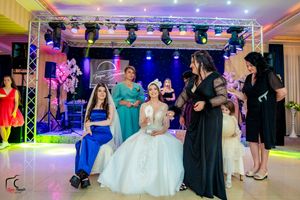 Wedding reception venue decorated with purple lighting and dance floor setup showing guests mingling and dancing.
