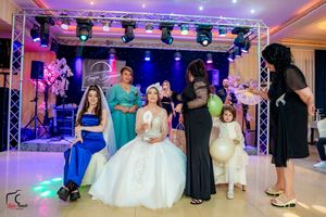 Panoramic view of a wedding reception ballroom with purple and blue mood lighting.