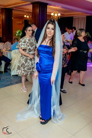 Wedding guests in formal attire mingling on dance floor under elegant chandeliers.