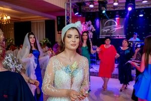 Panoramic view of wedding reception showing guests dancing under colorful stage lighting.