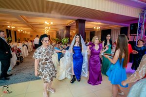 Wedding celebration showing guests in formal attire dancing under purple and blue lighting.