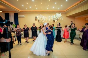 Wedding guests dance together in a ballroom with elegant chandeliers and mood lighting.