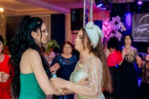 Two people share a dance moment at a wedding reception under vibrant purple lighting.