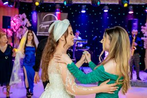 Wedding reception celebration with guests dancing on a colorfully lit dance floor with purple and blue lighting.