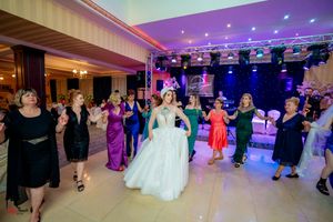 Wide angle shot of wedding reception ballroom with colorful lighting and dancing guests.