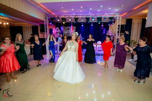 Wedding reception hall with dramatic lighting and guests dancing on illuminated floor.