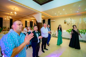 Wedding guests dance together in an elegant ballroom with crystal chandeliers and warm lighting.