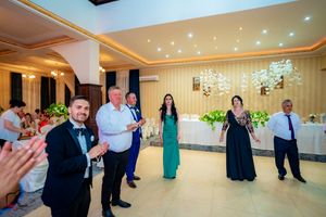 People dancing at a formal event in a luxurious ballroom with decorative lighting.