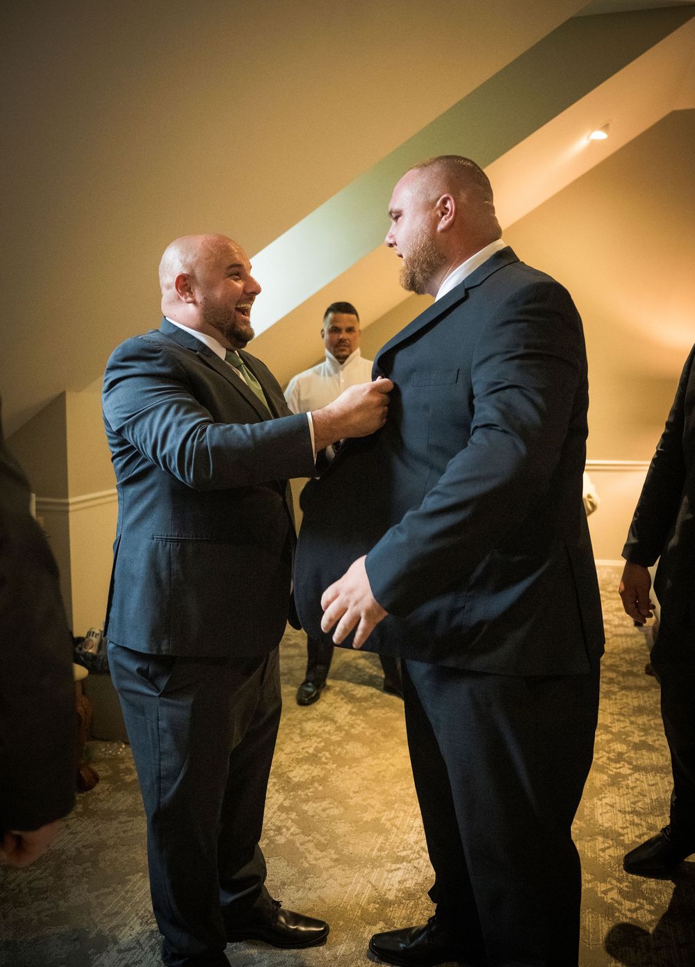 Groomsmen help adjust the groom's tie and suit before the wedding ceremony.