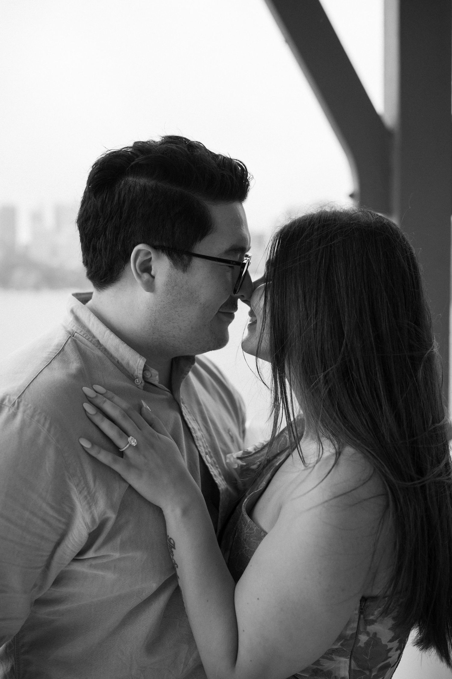 Intimate black and white portrait capturing tender moment between couple on balcony.