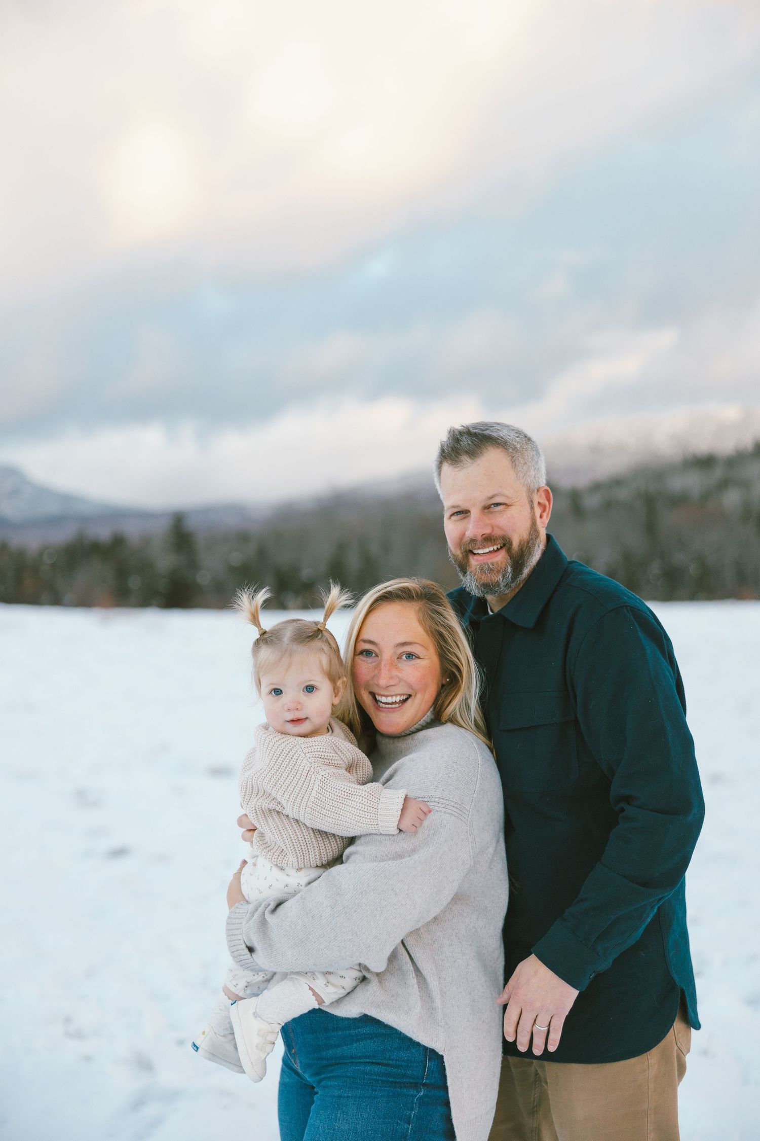 Winter family portrait session in the snow with mountains in background.