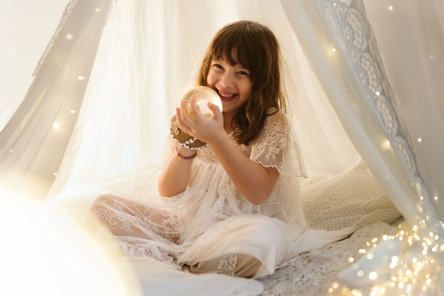 Glowing portrait in lace with white crystals and twinkle lights creating a magical atmosphere in a dreamy tent setup.