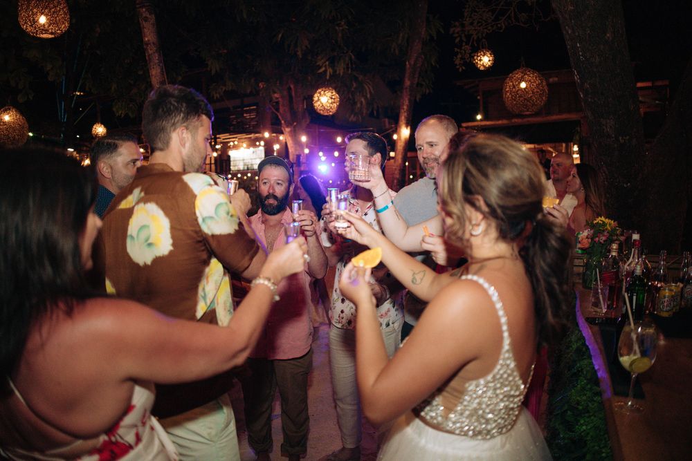 People dancing and celebrating at a nighttime party with glowing lanterns overhead.