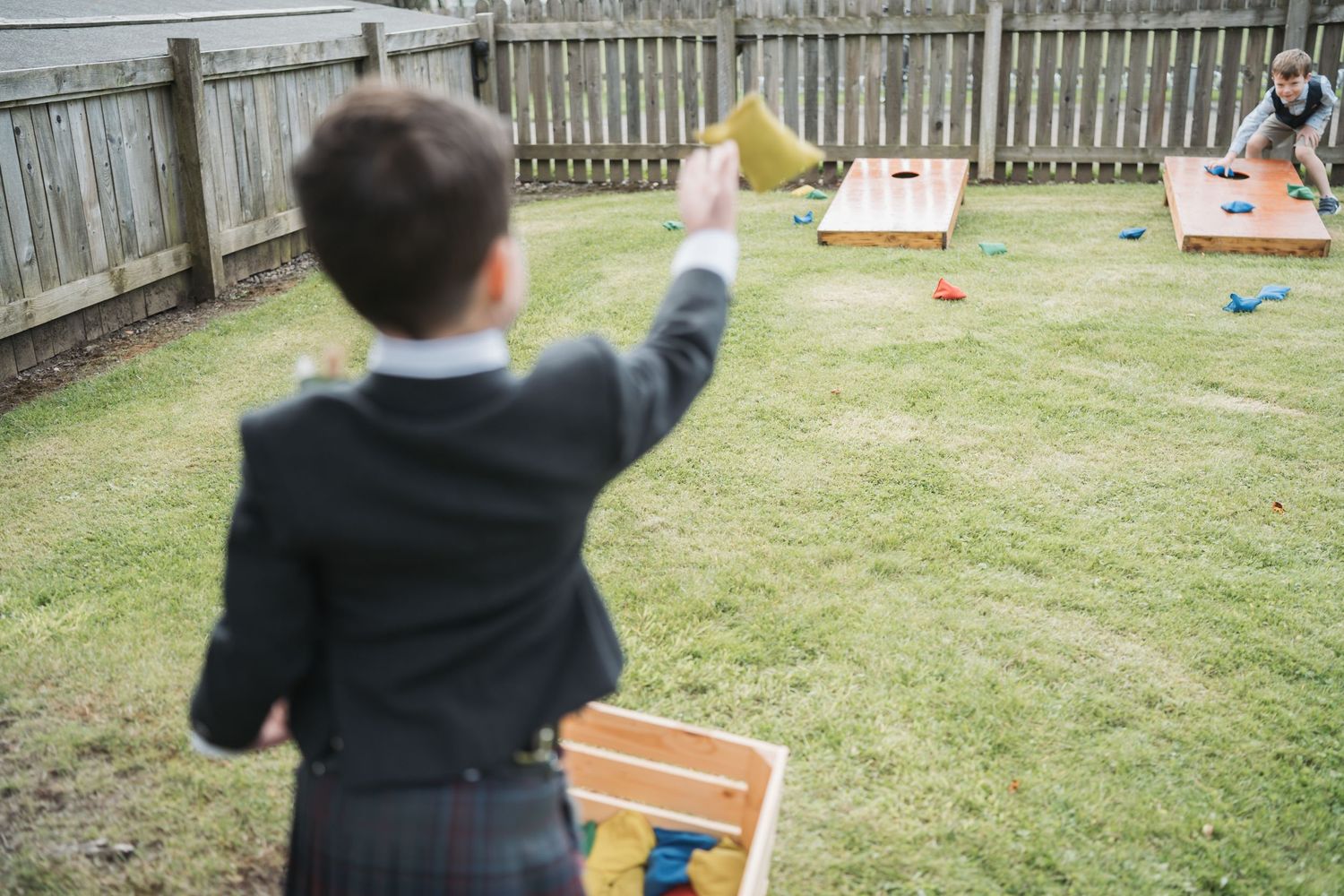 A young guest in formal attire plays a backyard carnival game at what appears to be a party or event.