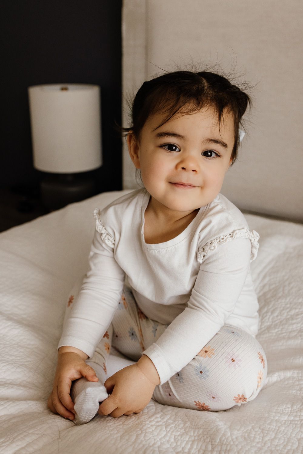 Toddler smiles at camera during in-home family newborn photo session with Cindy Tucey Photography in San Jose