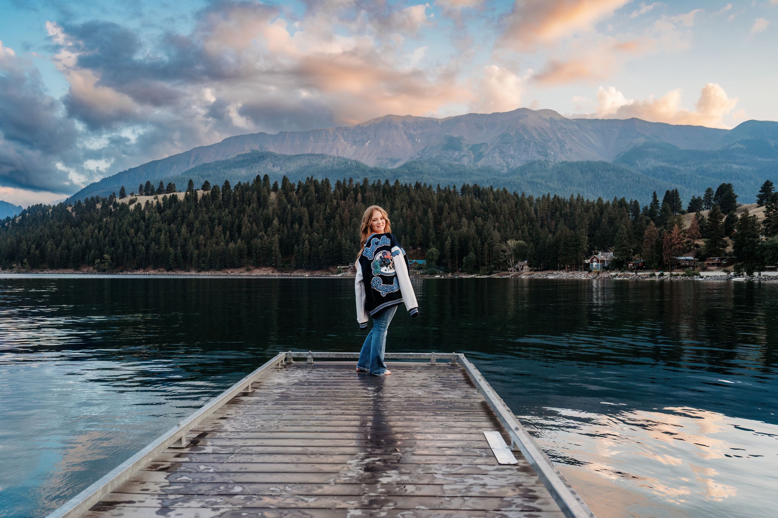 Person standing on wooden dock over lake with mountain backdrop at sunset. Wallowa Lake, Joseph, Oregon