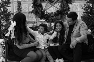 Family sharing a playful moment together on couch surrounded by Christmas decorations in black and white.