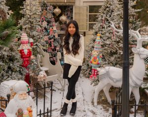 Winter scene with decorated Christmas trees, reindeer figures, and holiday decorations in snowy setting.