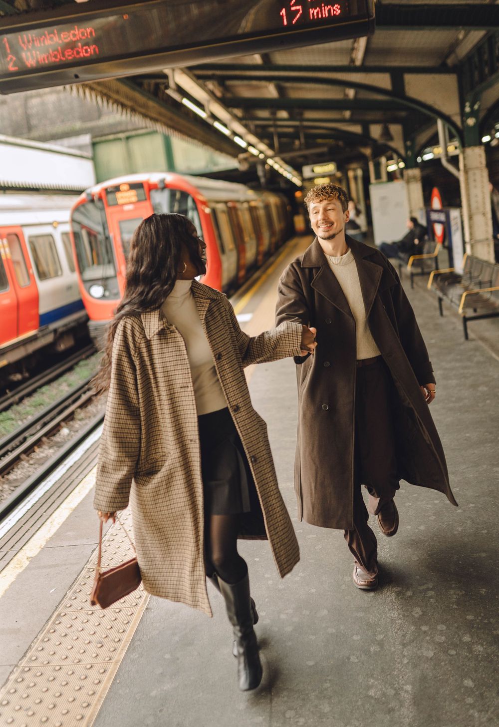 Two people walking on a subway platform in casual winter attire, captured in a sequence of motion.