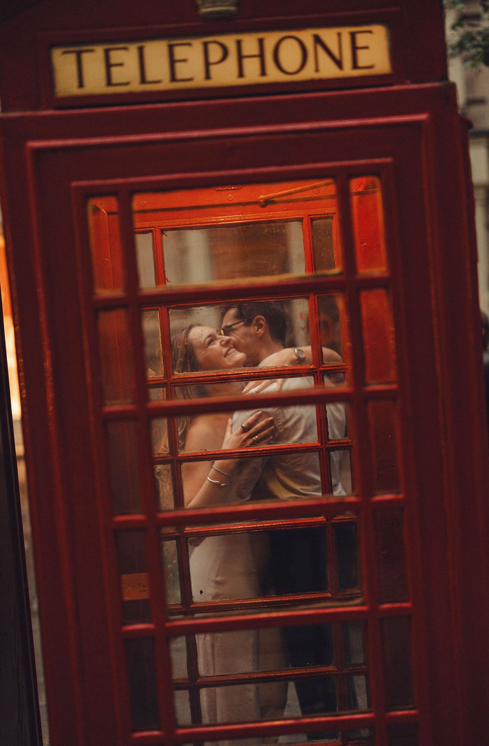 Couple shares intimate moment inside iconic red British telephone booth in London.