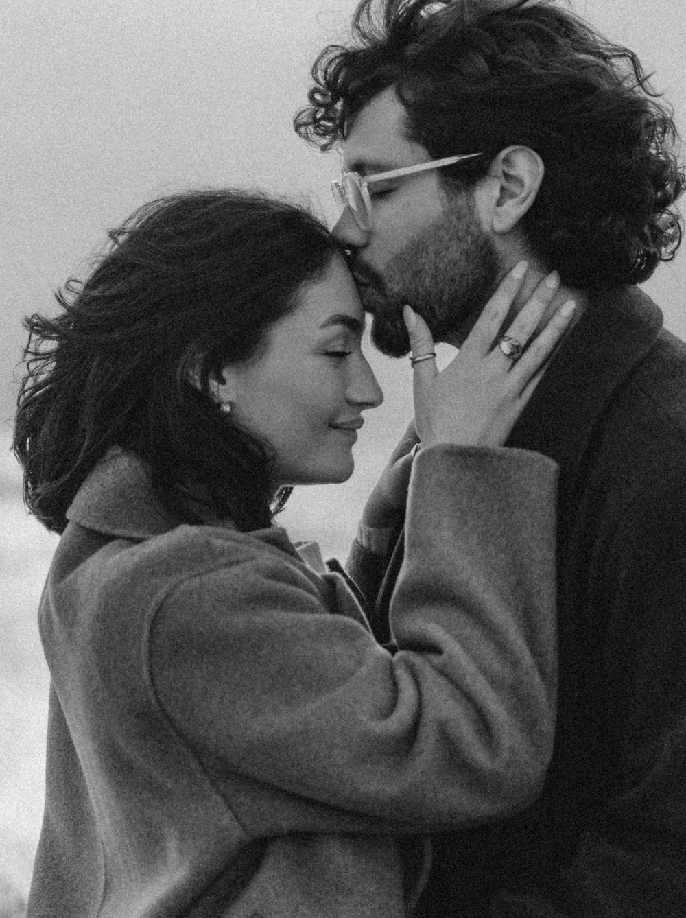 Black and white series showing tender moments between a couple in winter coats.