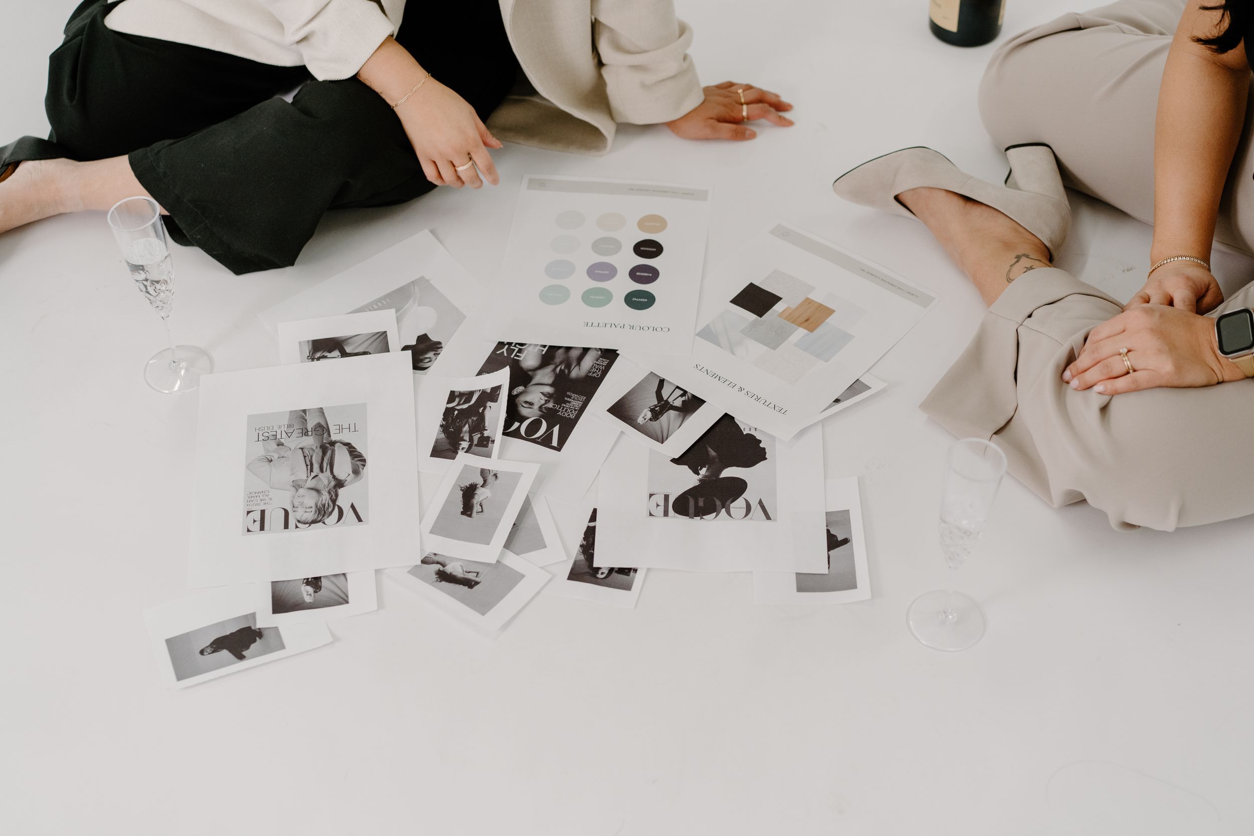 Polaroid photographs and color swatches scattered on white surface with people sitting around reviewing them.
