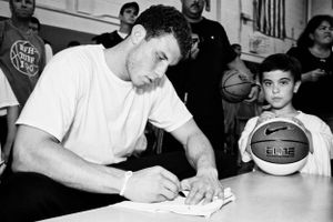 A black and white candid image shows a Blake Griffin autograph signing session with a basketball fan holding a Nike basketball nearby.