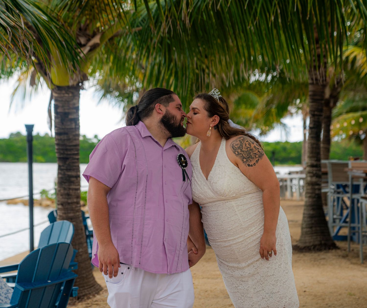 Romantic couple sharing an intimate moment under palm trees at a tropical beach destination.