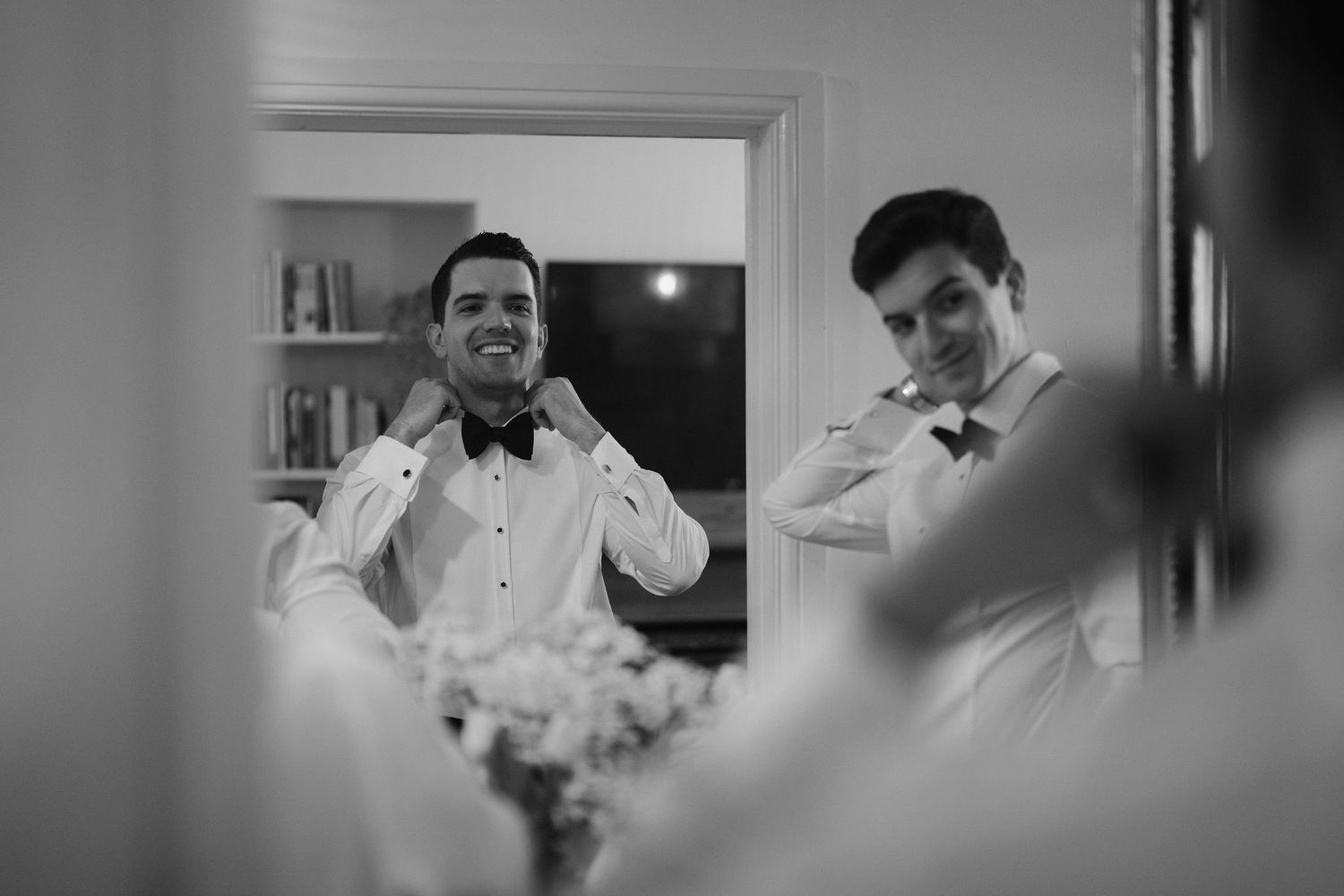 groom adjusting bow tie in mirror while getting ready at hamswell house in bath