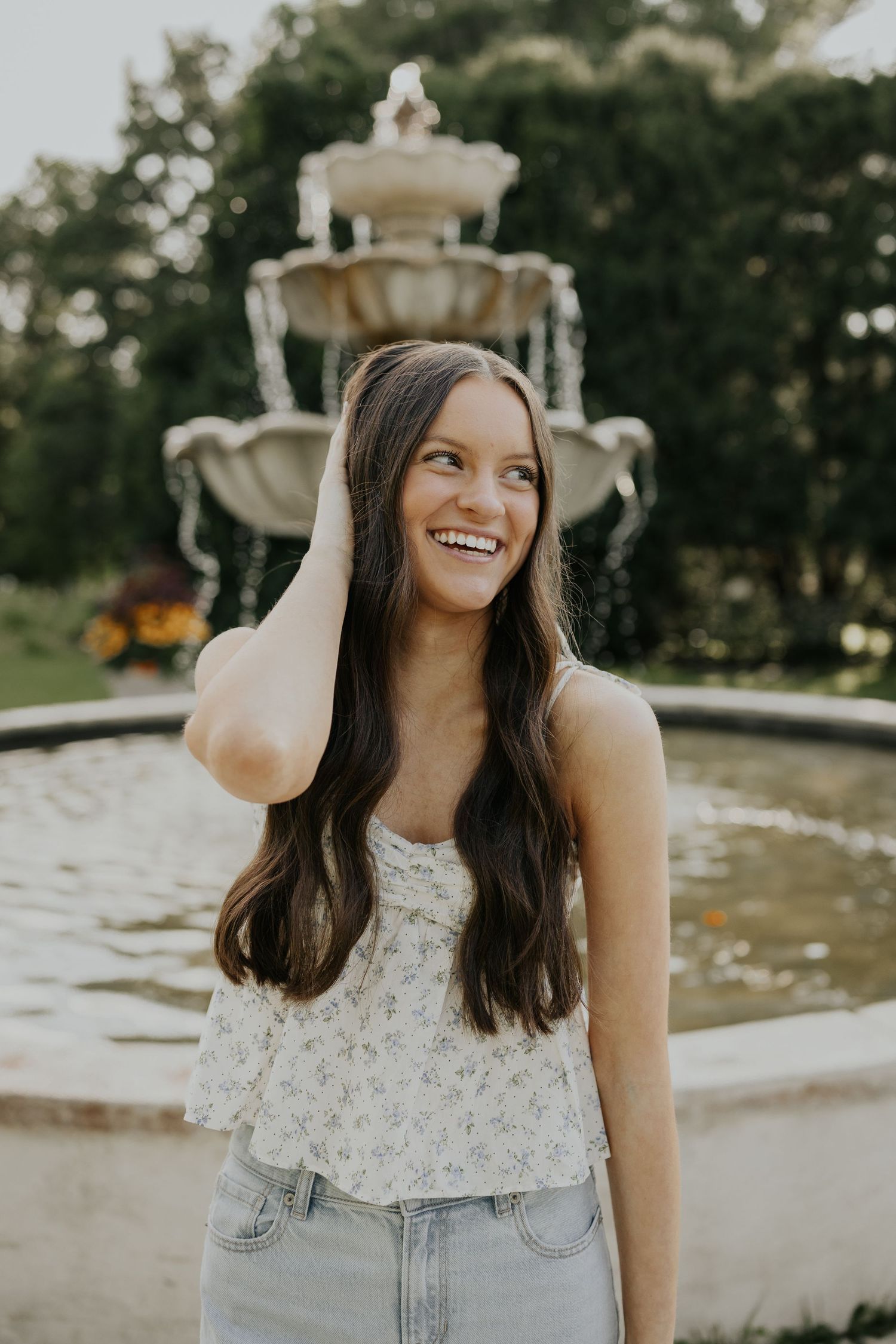 Smiling in front of a fountain at Arneson Acres park for Senior portraits in Edina MN.