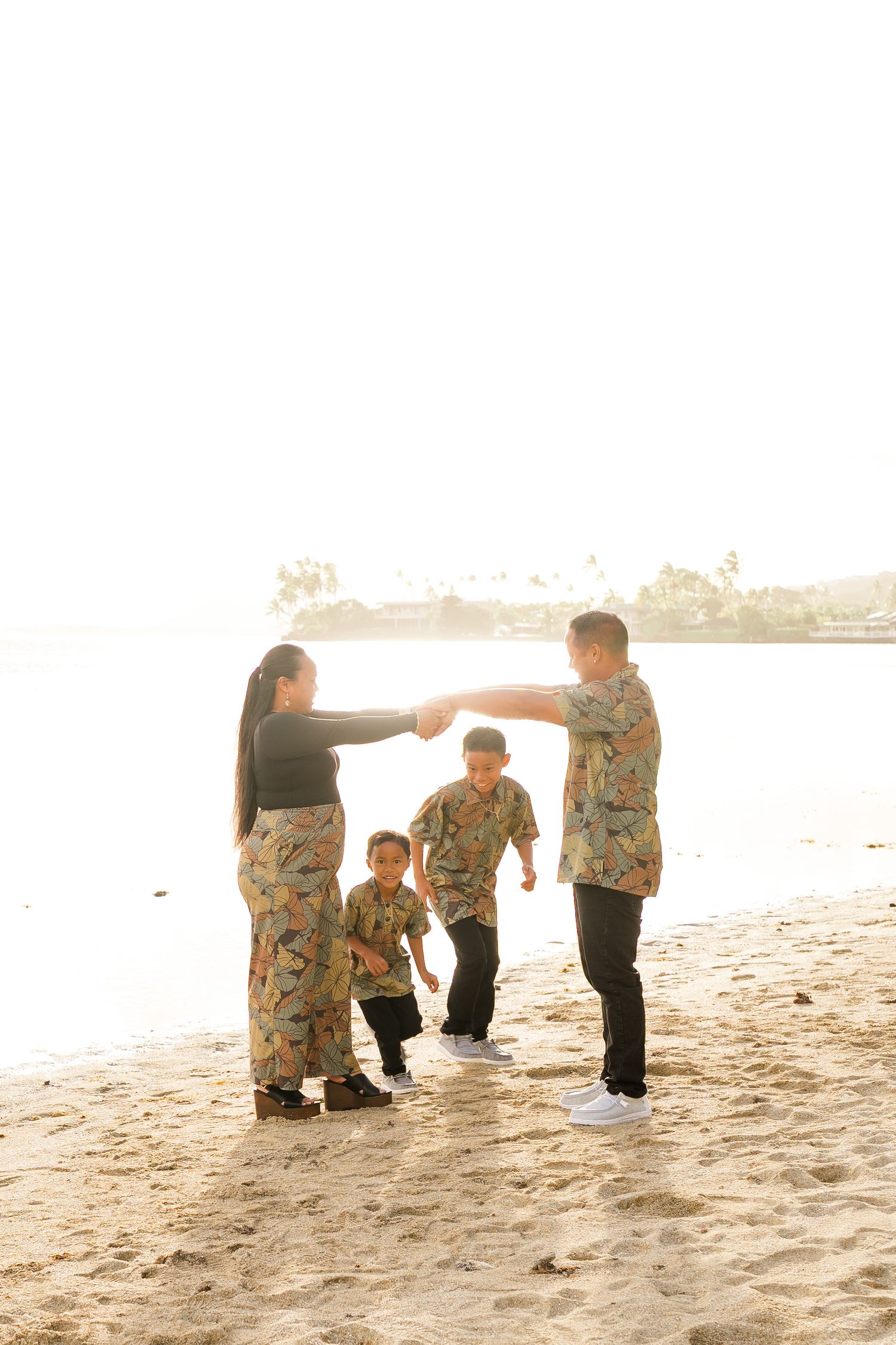 A family in coordinated camouflage outfits plays together on a sunny beach at golden hour.