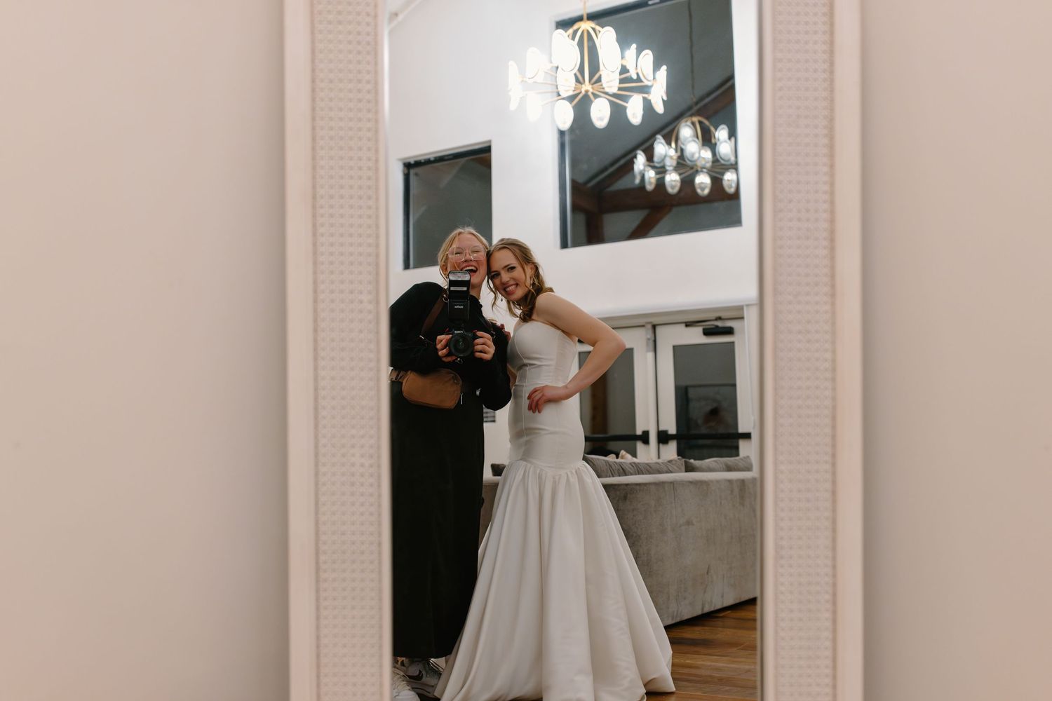 A wedding venue hallway with elegant decor and a white dress visible in the mirror reflection.