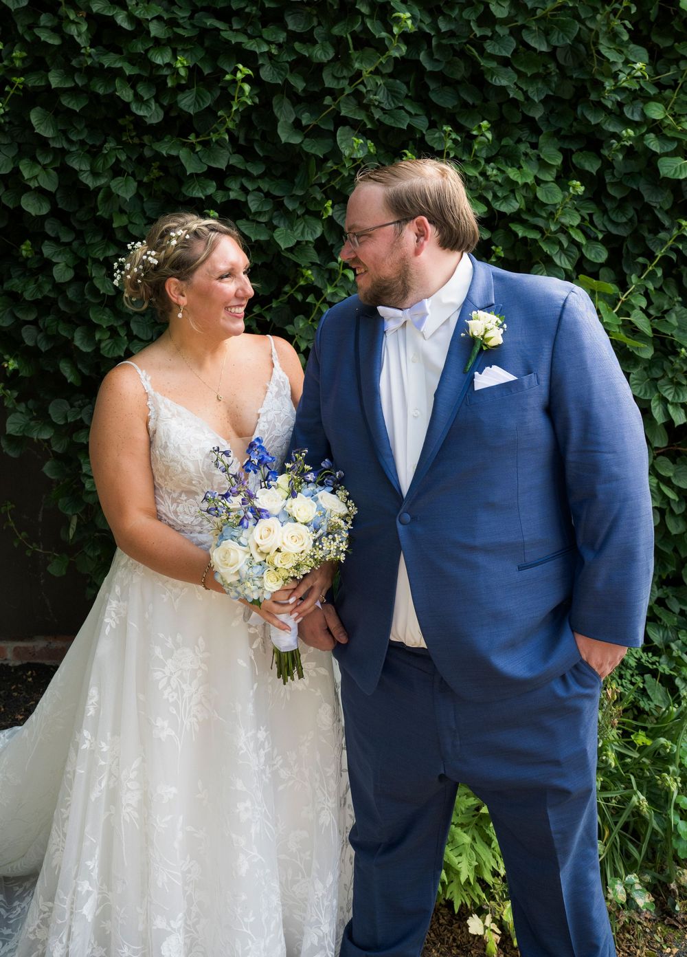 A romantic garden photo session with lush greenery backdrop and elegant wedding attire in blue and white.