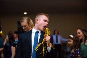 Wedding guests dancing and celebrating at a reception with yellow decorative elements.