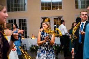 Guests dancing and celebrating at an indoor wedding reception with hardwood floors.
