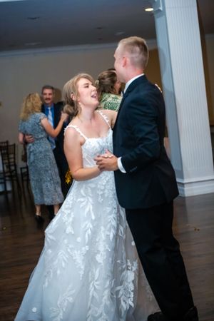 A couple shares a romantic dance in a beautiful white wedding gown and black tuxedo.