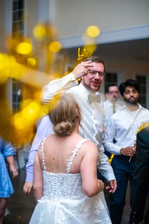 Wedding celebration with guests dancing under warm lighting and yellow decorations.
