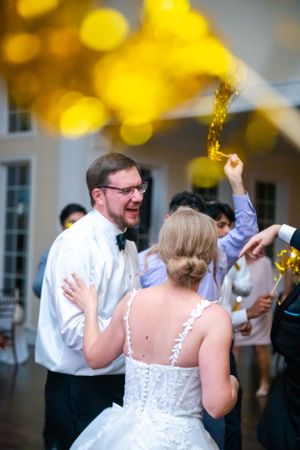 Wedding party dancing and celebrating with yellow bokeh lights in the background.