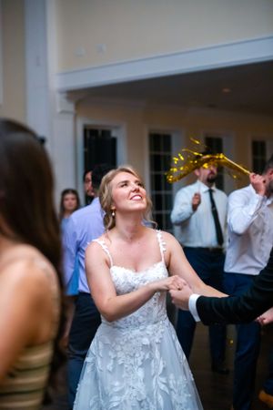 A bride in a white lace dress dancing joyfully at her wedding reception.