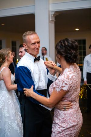 Wedding guests dancing together in a ballroom with white columns and warm lighting.