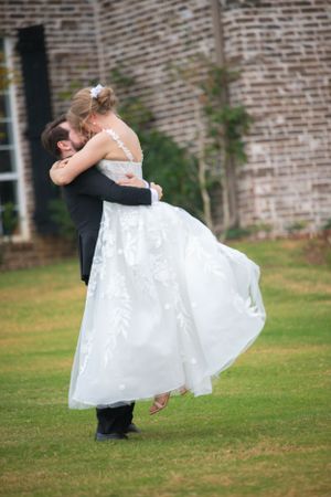 Elegant couple shares a romantic dance moment on a lawn during their wedding.