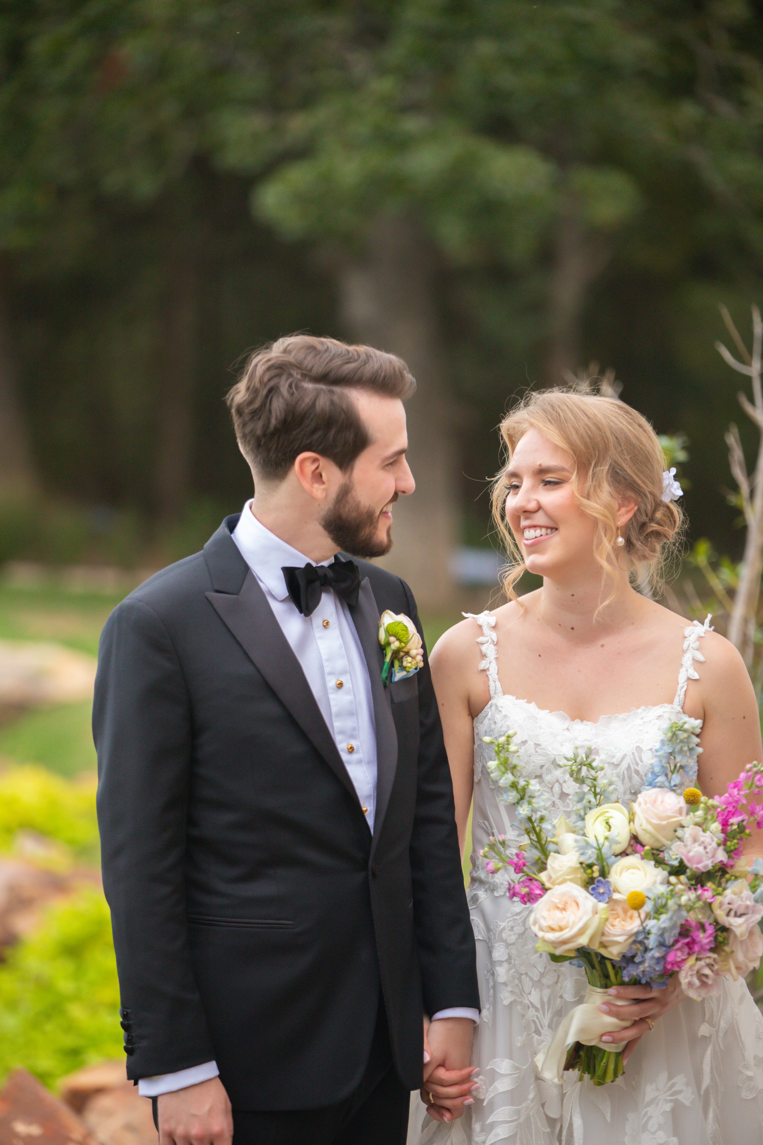 Bride holding colorful bouquet shares happy moment with groom in garden setting.
