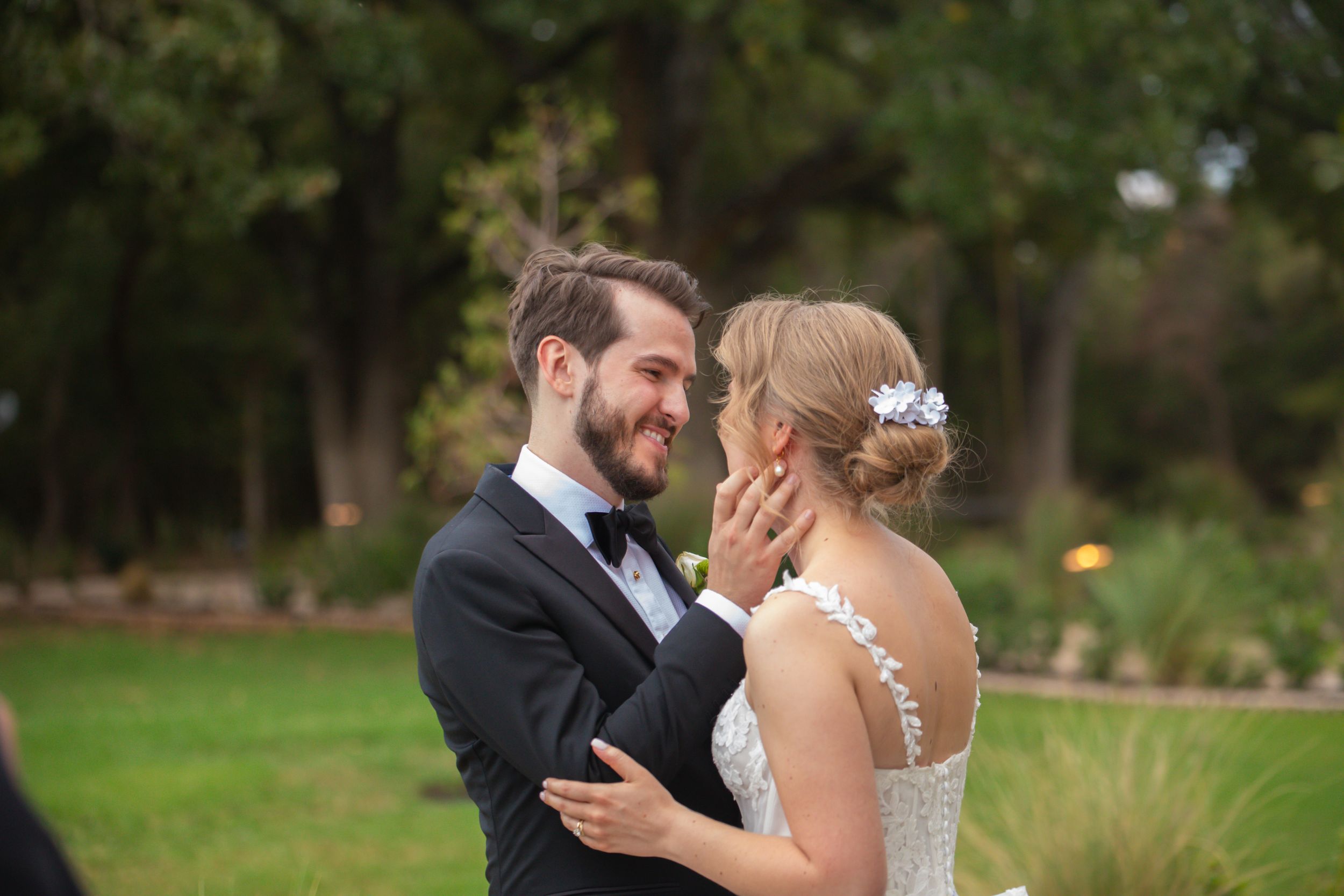 Wedding couple shares joyful moments together outdoors near greenery.