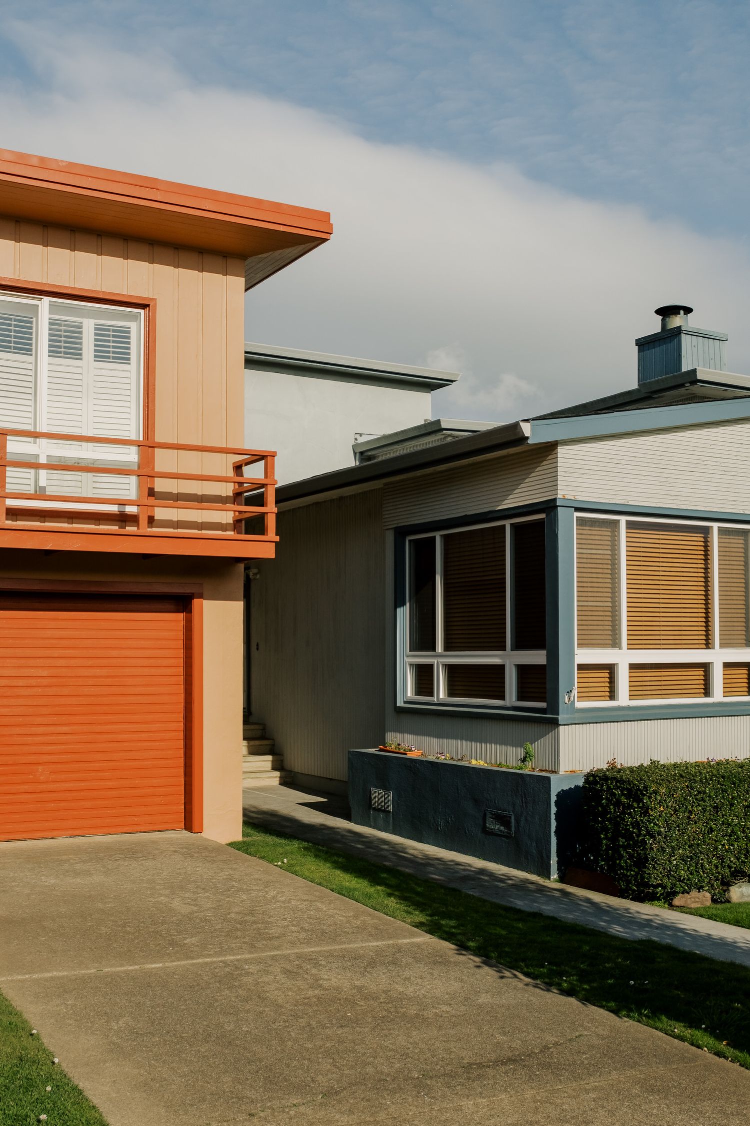 Modern mid-century residential architecture with orange and gray exterior featuring a garage and angular windows.