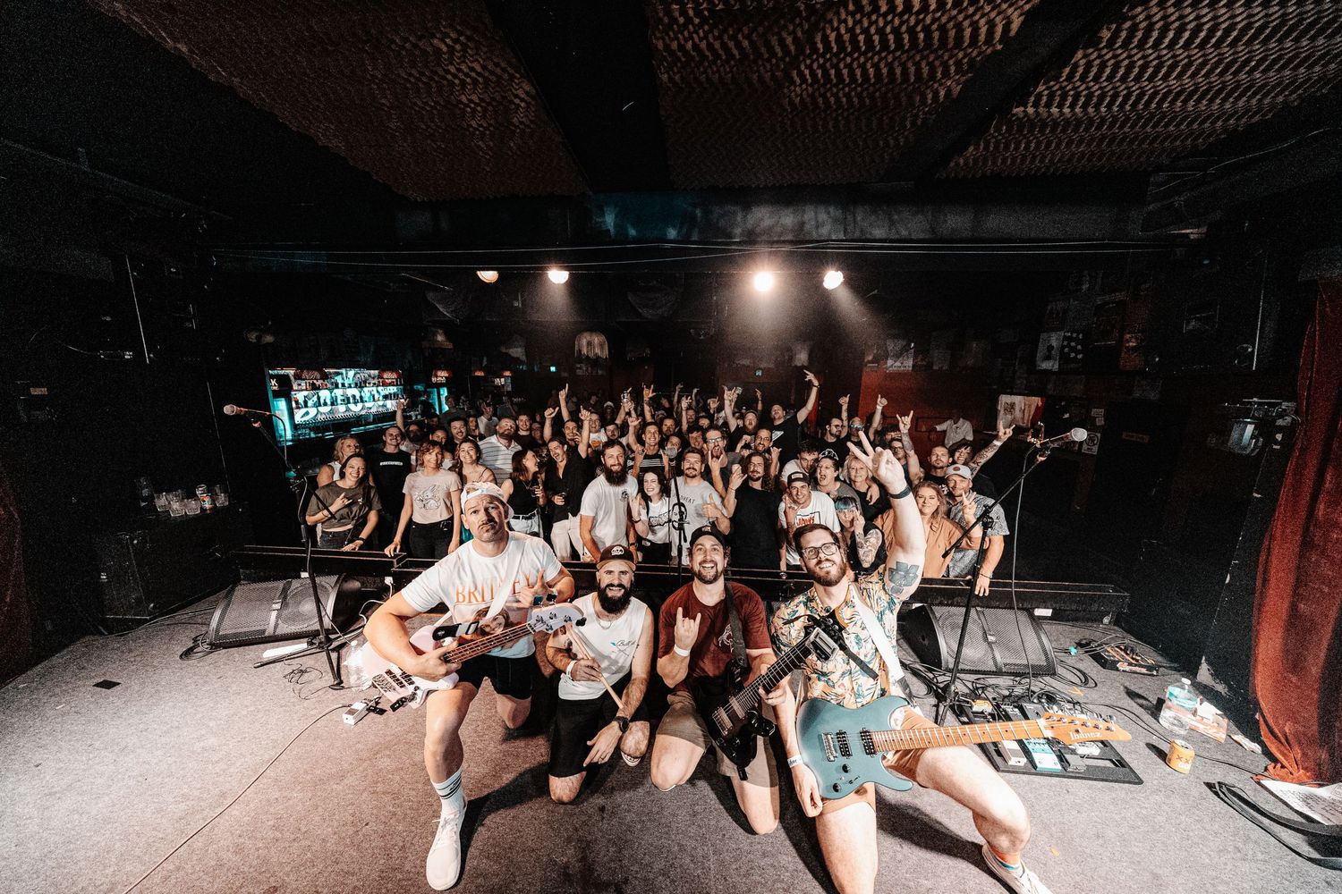 Large group poses together for an enthusiastic group photo at a music venue.
